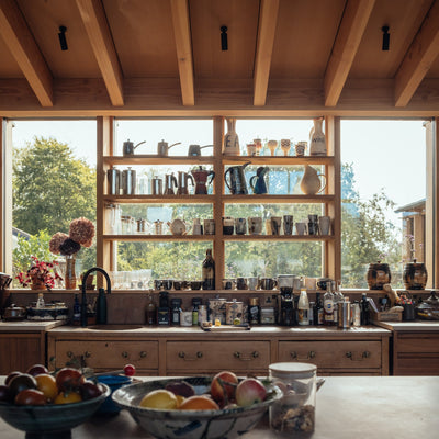 Exterior of the rammed earth house in Wiltshire by Tuckey Design Studio, showing textured earth walls and natural landscaping